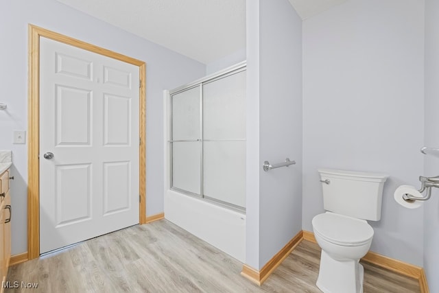 full bathroom with hardwood / wood-style floors, toilet, shower / bath combination with glass door, and vanity