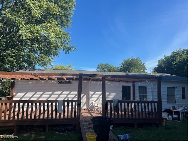 rear view of property featuring a pergola and a deck