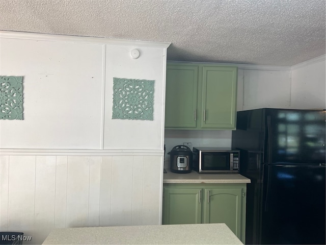 kitchen with green cabinets, black refrigerator, and a textured ceiling