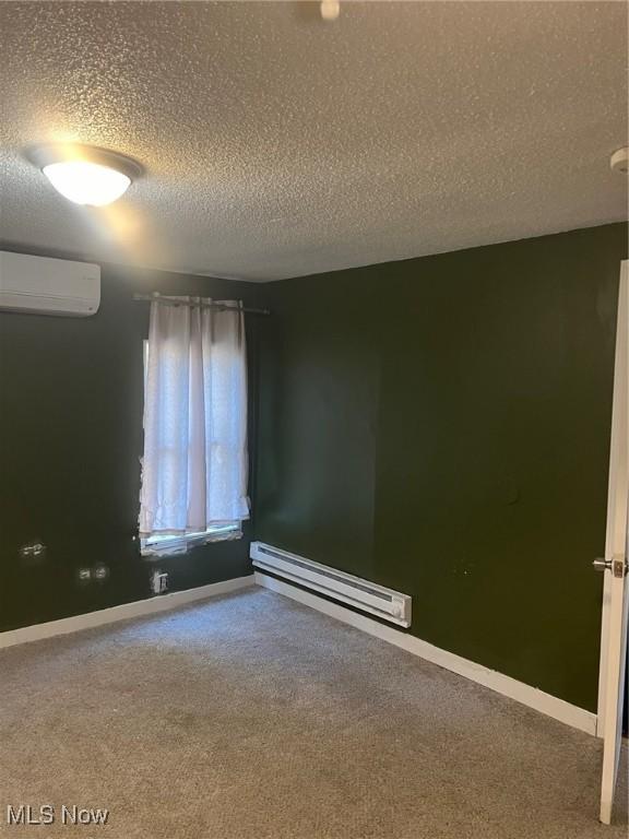 spare room featuring baseboard heating, carpet, a wall mounted air conditioner, and a textured ceiling