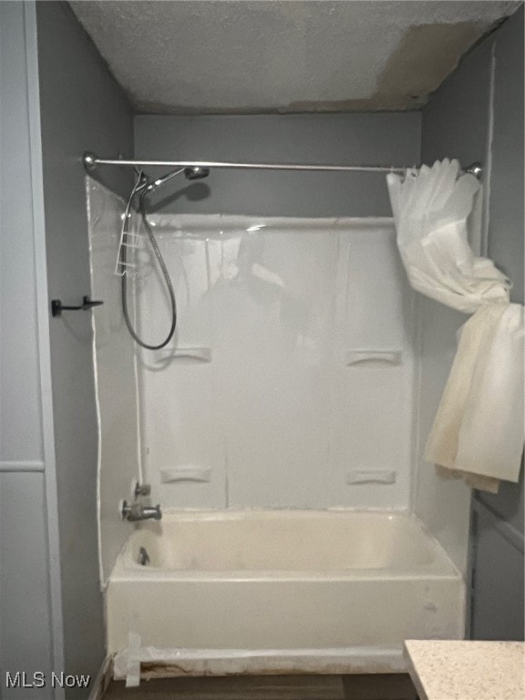 bathroom with shower / bathing tub combination, vanity, and a textured ceiling