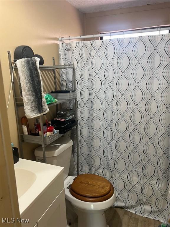 bathroom with toilet, hardwood / wood-style floors, vanity, a textured ceiling, and a shower with shower curtain