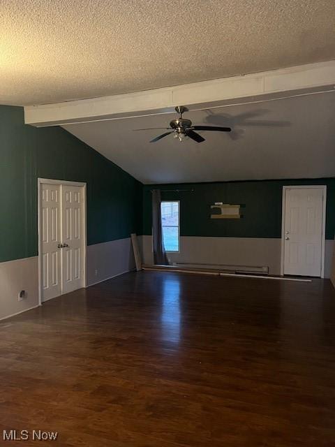 unfurnished living room with vaulted ceiling with beams, a textured ceiling, and wood finished floors