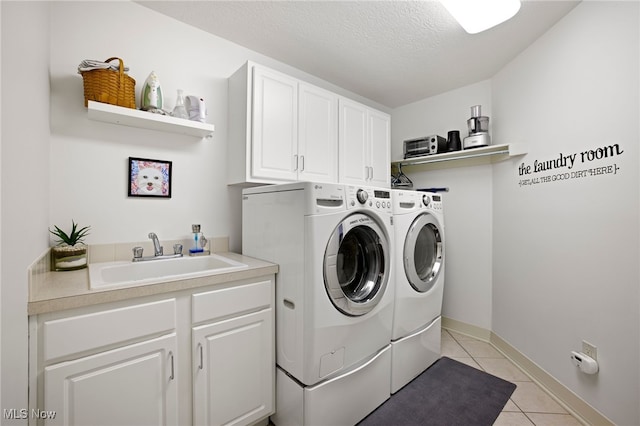 laundry area featuring a textured ceiling, cabinets, light tile patterned floors, independent washer and dryer, and sink