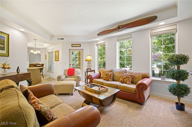 carpeted living room with a tray ceiling, crown molding, and a chandelier