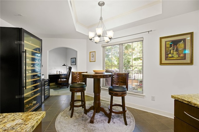 tiled dining room featuring a raised ceiling, an inviting chandelier, and wine cooler