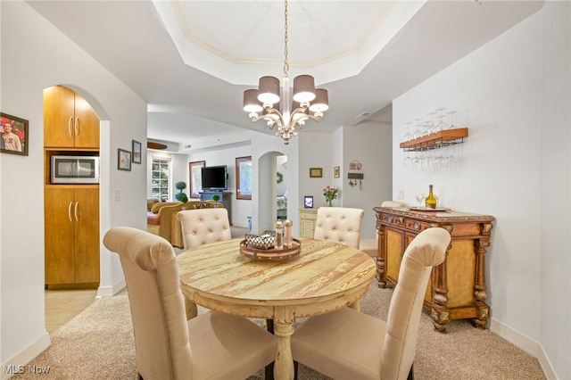 carpeted dining space featuring a raised ceiling and a notable chandelier