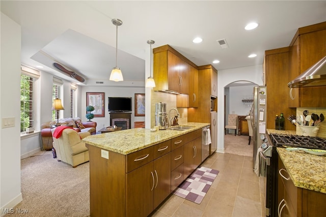 kitchen featuring decorative light fixtures, light carpet, appliances with stainless steel finishes, kitchen peninsula, and sink