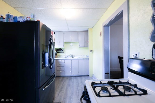 1631 Globe St, East Liverpool, OH 43920 - kitchen with black fridge with ice dispenser, gas stove, a drop ceiling, a sink, and light countertops