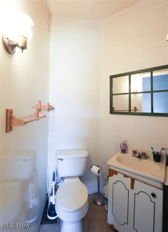 bathroom with vanity, a textured ceiling, toilet, and tile patterned flooring