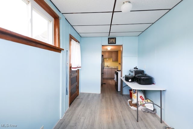 corridor with a paneled ceiling and light wood-type flooring