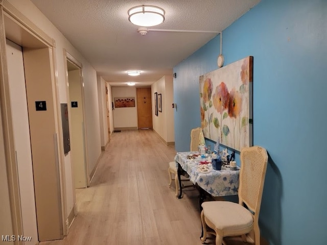 hallway with a textured ceiling and light wood-type flooring