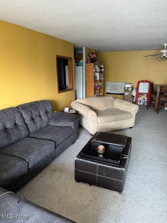 living room featuring ceiling fan, carpet floors, and a textured ceiling