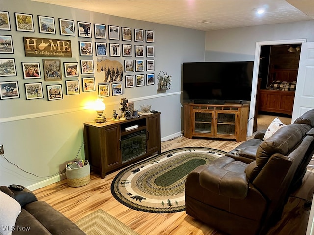 living room featuring light wood-type flooring, a textured ceiling, and a fireplace