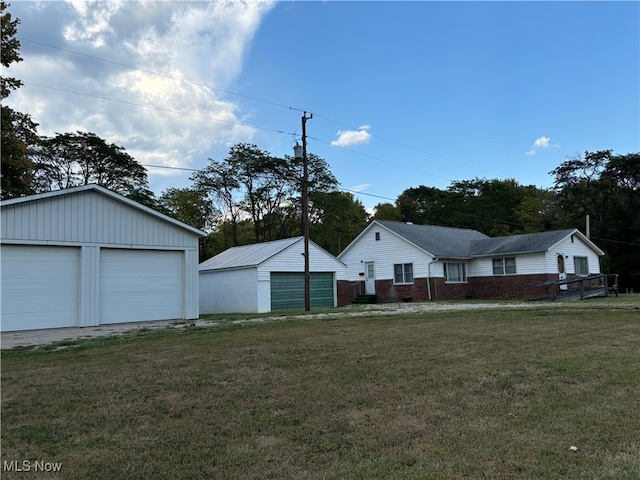 exterior space featuring a garage, a front lawn, and an outdoor structure