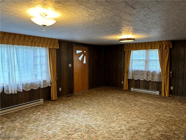 carpeted empty room with a baseboard heating unit and wooden walls