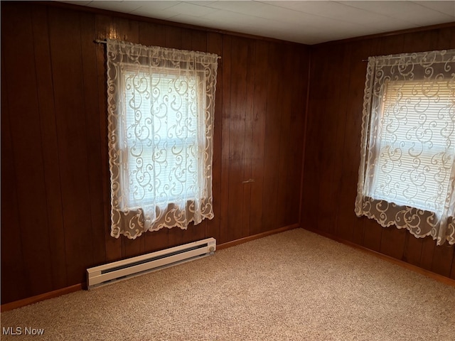 spare room featuring baseboard heating, wood walls, and carpet floors