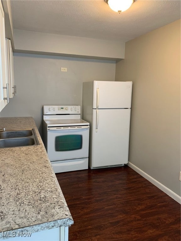 kitchen with white appliances, dark hardwood / wood-style floors, a textured ceiling, and sink