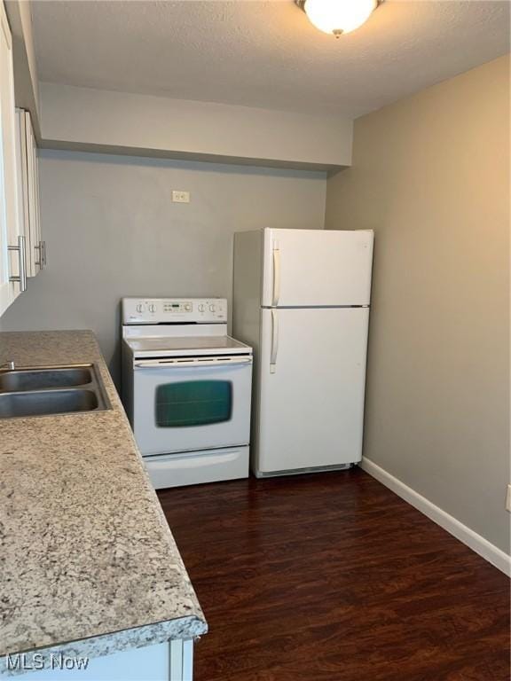 kitchen with white appliances, baseboards, dark wood-style flooring, light countertops, and a sink