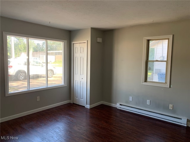 spare room with dark wood-type flooring, a textured ceiling, and a baseboard radiator