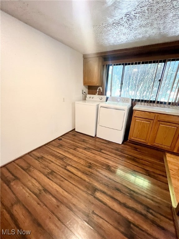 laundry area with a textured ceiling, cabinets, dark hardwood / wood-style floors, and washing machine and dryer