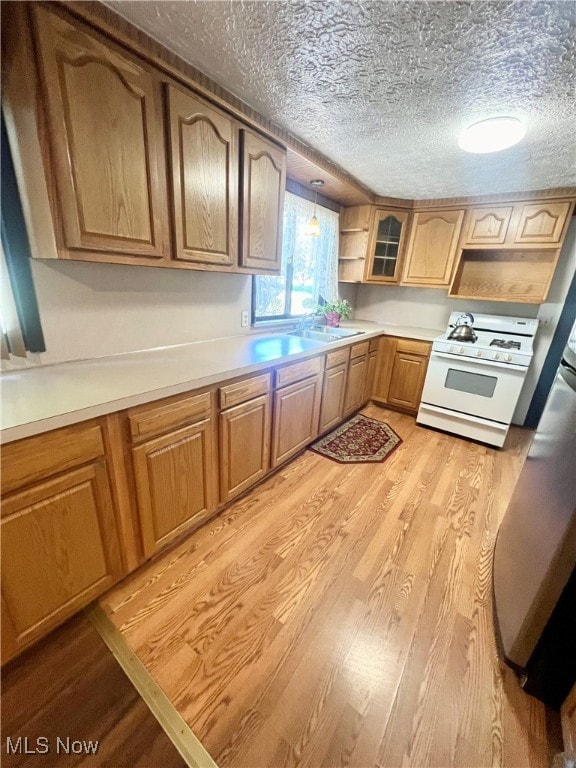 kitchen with gas range gas stove, light hardwood / wood-style flooring, decorative light fixtures, and a textured ceiling