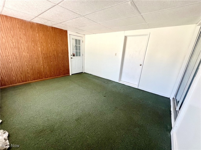 unfurnished bedroom featuring wood walls, a paneled ceiling, a closet, and carpet floors