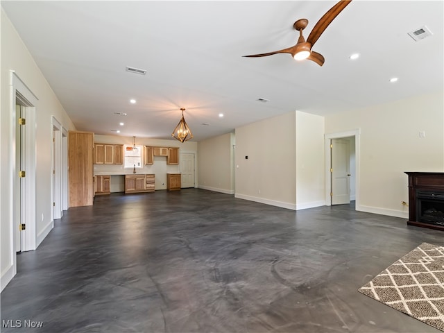 unfurnished living room featuring ceiling fan and sink