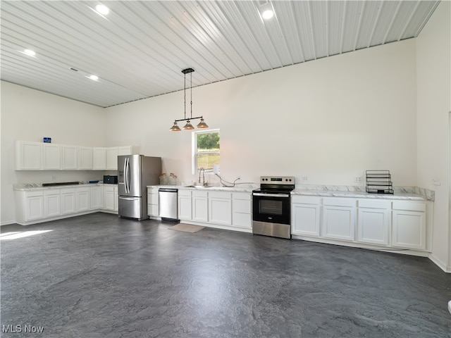 kitchen featuring a towering ceiling, white cabinets, stainless steel appliances, and decorative light fixtures