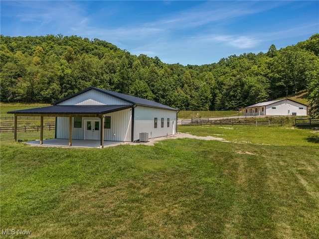 rear view of property with a lawn and central air condition unit