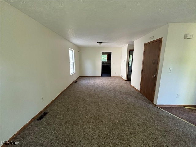 unfurnished room featuring visible vents, a textured ceiling, baseboards, and carpet floors