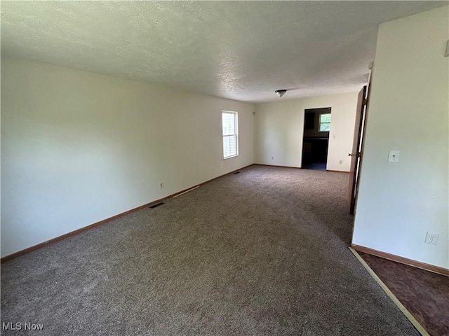 empty room with visible vents, baseboards, carpet floors, and a textured ceiling