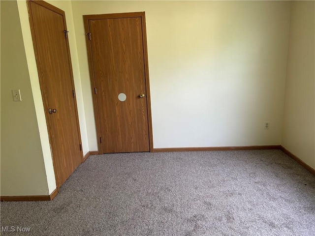 unfurnished bedroom with a closet, baseboards, and carpet floors