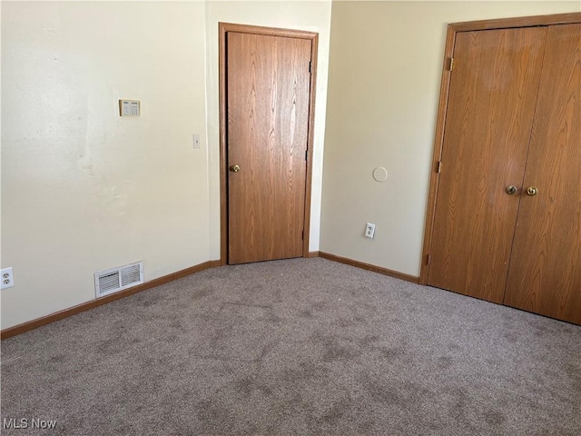 unfurnished bedroom with a closet, visible vents, baseboards, and carpet floors