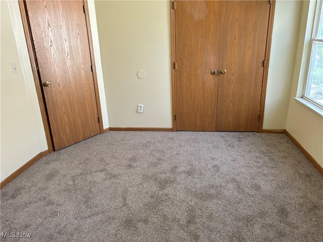 unfurnished bedroom featuring a closet, carpet floors, and baseboards