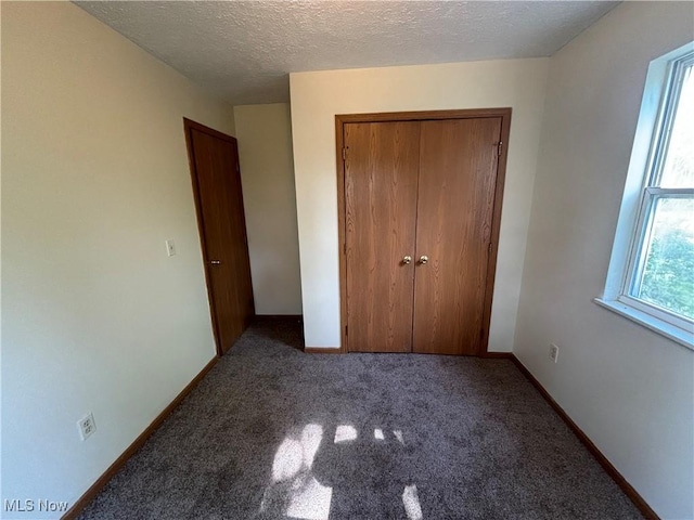 unfurnished bedroom with a closet, baseboards, carpet, and a textured ceiling