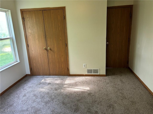 unfurnished bedroom featuring a closet, visible vents, baseboards, and carpet floors