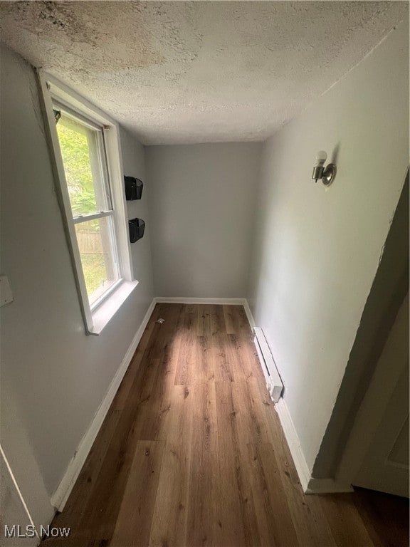 interior space featuring dark hardwood / wood-style flooring, a baseboard radiator, and a textured ceiling