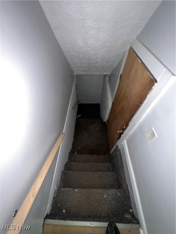 staircase with a textured ceiling and vaulted ceiling