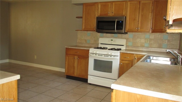 kitchen featuring sink, tasteful backsplash, white range with gas cooktop, and light tile patterned flooring