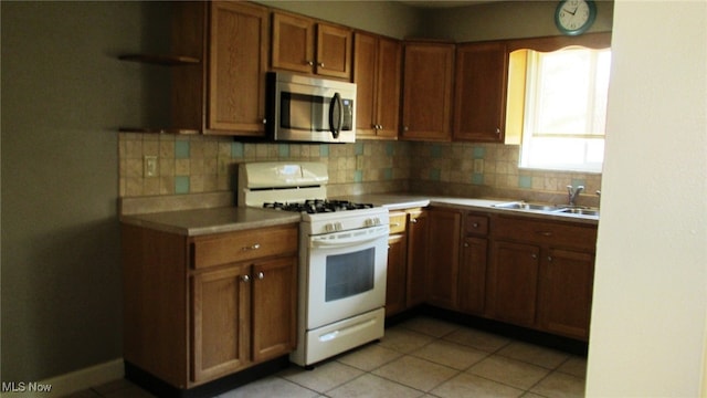 kitchen featuring sink, white gas range oven, light tile patterned floors, and tasteful backsplash