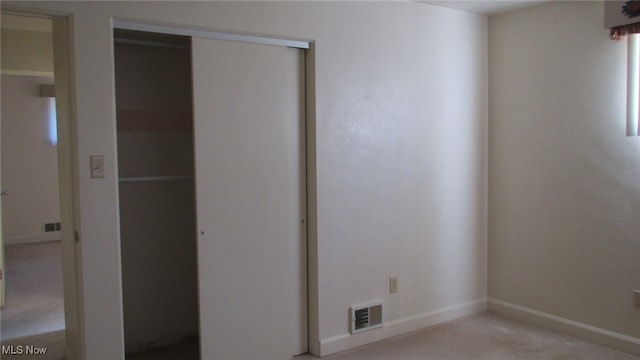 unfurnished bedroom featuring a closet and light colored carpet