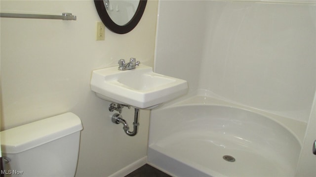 bathroom featuring sink, a shower, and toilet