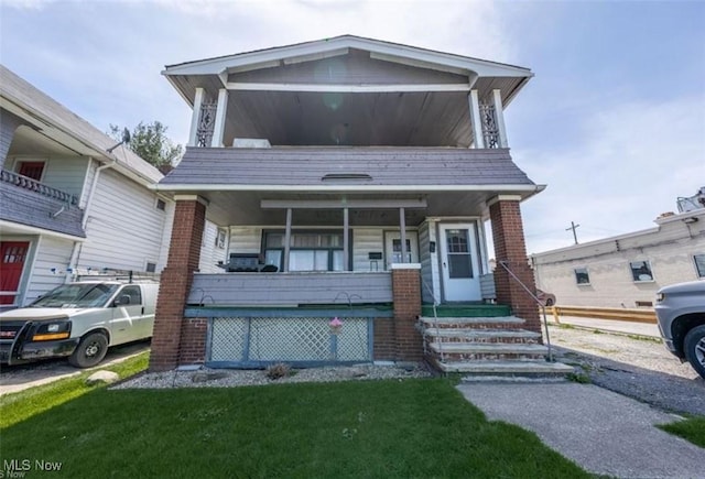 view of front of house featuring a porch, a front lawn, and brick siding