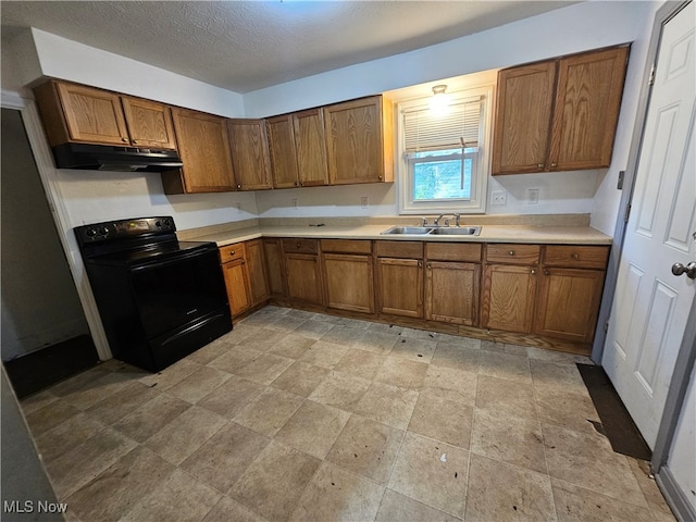 kitchen featuring brown cabinetry, black / electric stove, light countertops, under cabinet range hood, and a sink