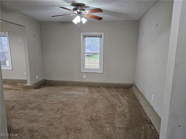 carpeted spare room with a ceiling fan and a textured ceiling