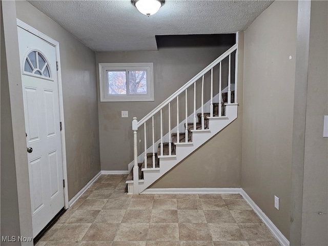 foyer with stairs, baseboards, and a textured ceiling