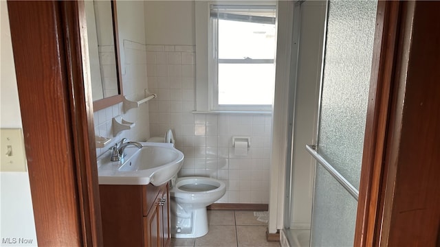 bathroom featuring tile patterned flooring, vanity, toilet, and tile walls