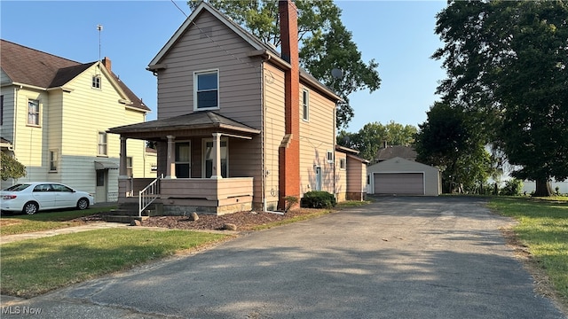 view of front property with a porch, a garage, an outdoor structure, and a front yard