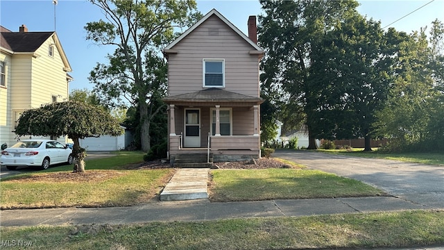 front of property featuring a front yard, covered porch, and a garage